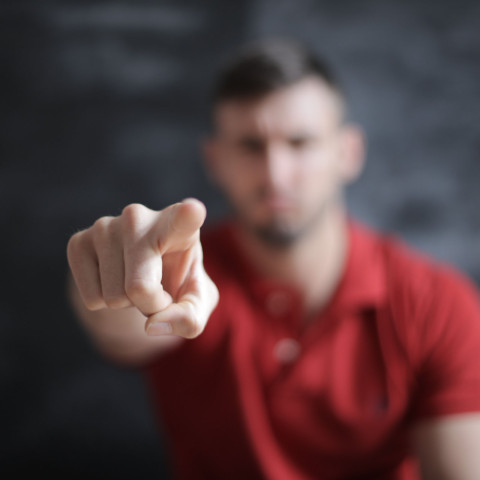 Man wijst met zijn vinger richting de camera; de vinger is scherp in beeld, zijn gezicht onscherp.